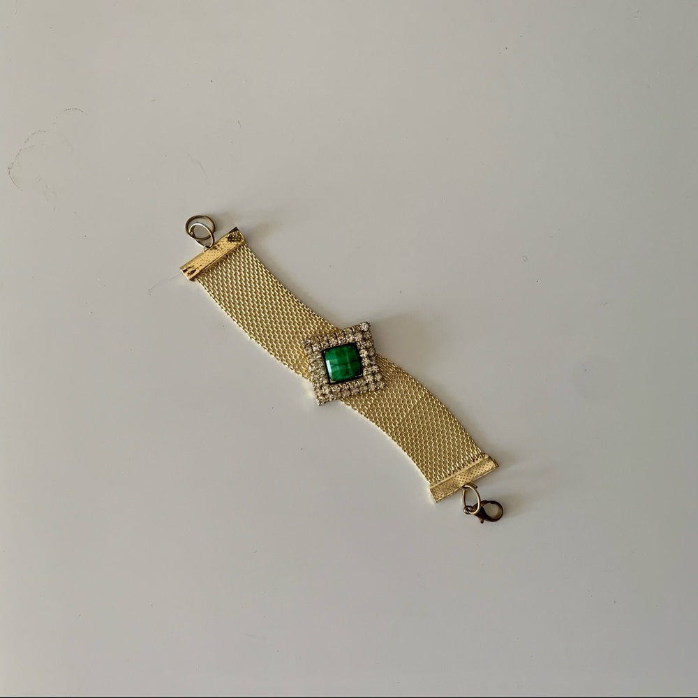Gold tone bracelet with green stone in center.